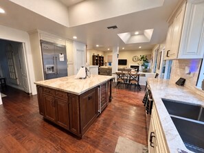 A kitchen with a central island, wooden cabinets, a built-in oven, and a dining area with chairs. - Agoura Hills Retreat - Malibu Beaches and Mountain Trails (Agoura Hills)