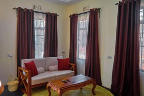 A living room with a sofa, a coffee table, and curtains.