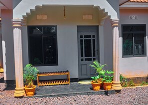 A building entrance with a bench, potted plants, and a door.