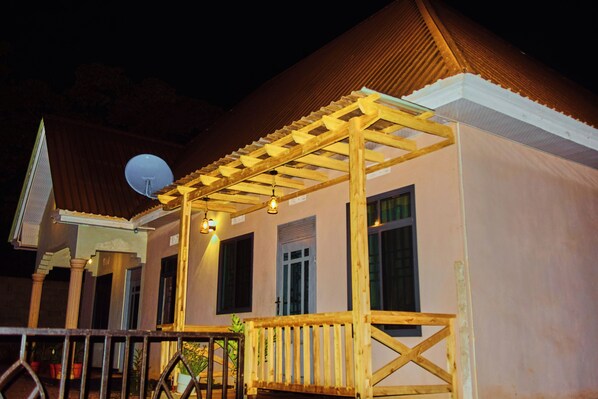 A building with a wooden porch, a satellite dish, and a window with shutters.