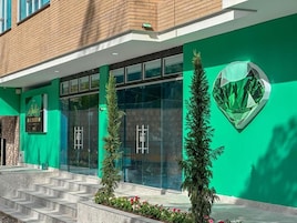 Un edificio con fachada verde, entrada de vidrio y una escalera que conduce a la entrada.
