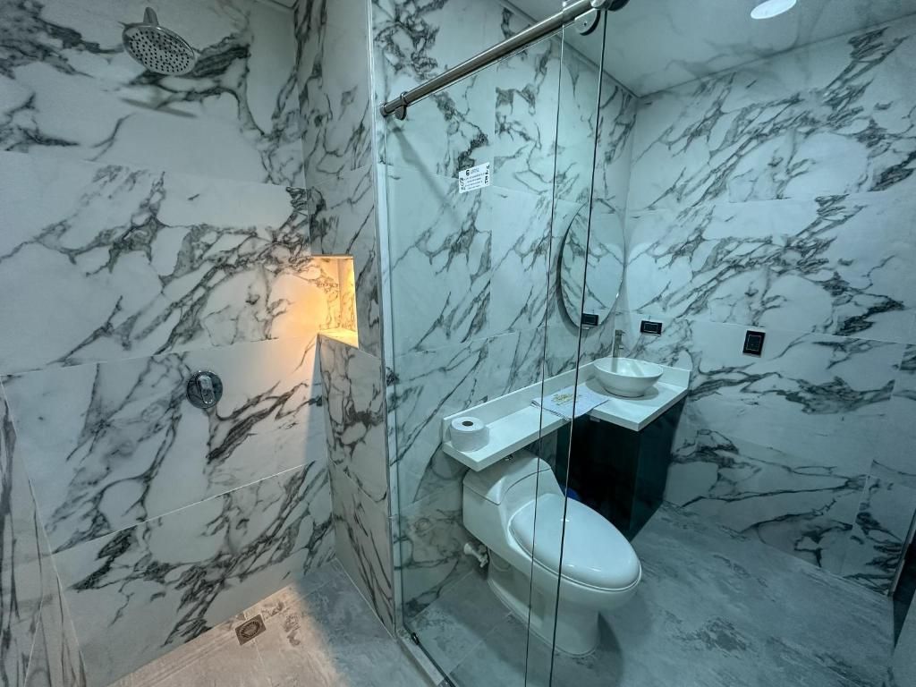 Ein Badezimmer mit Marmorboden und -wänden, einer Toilette, einem Waschbecken und einer Duschkabine.