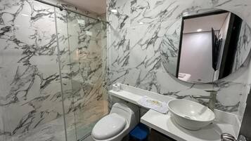 Ein Badezimmer mit Marmorverkleidung, einer Toilette, einem Waschbecken und einem Spiegel.