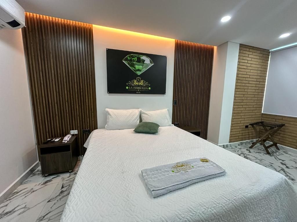 A hotel room with a bed, a nightstand, a wall-mounted picture, and a brick-patterned wall.