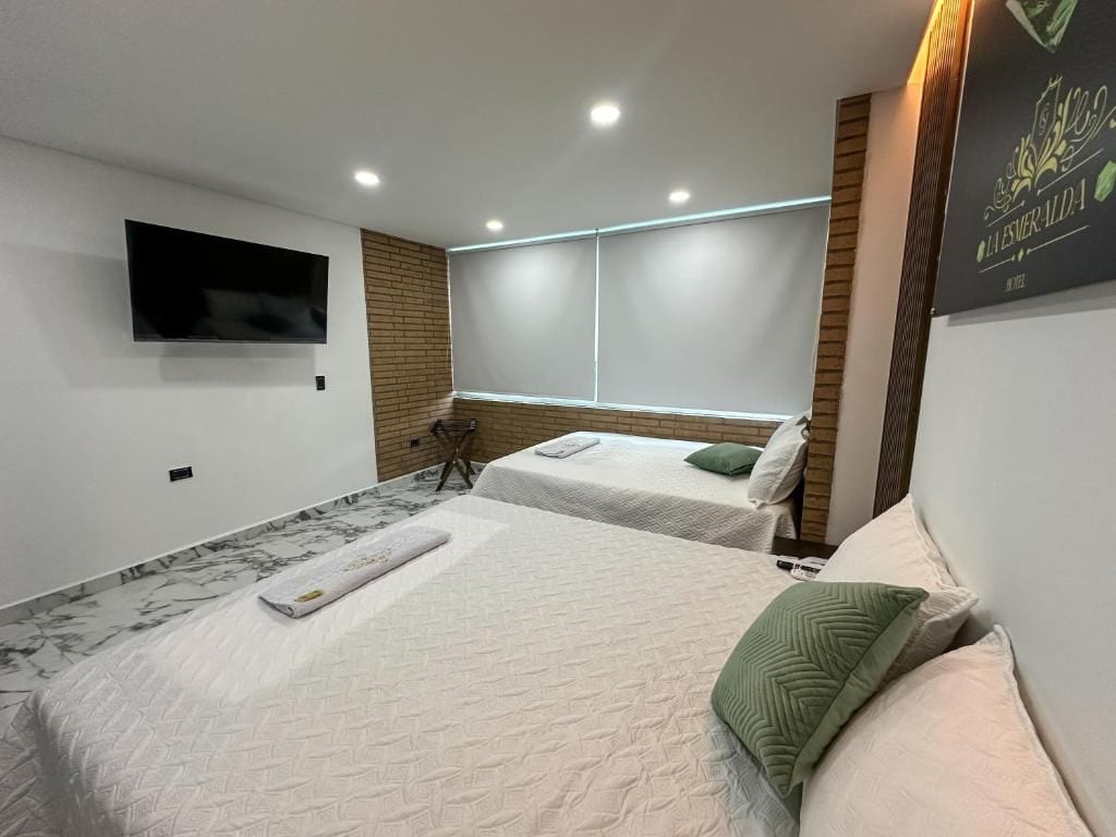 A hotel room with two beds, a flat-screen TV mounted on the wall, and a wooden accent wall.