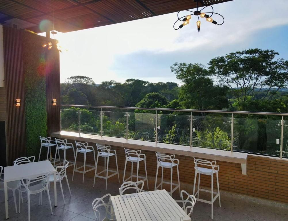 An outdoor seating area with tables and chairs, a glass railing, and a view of the surrounding forest.