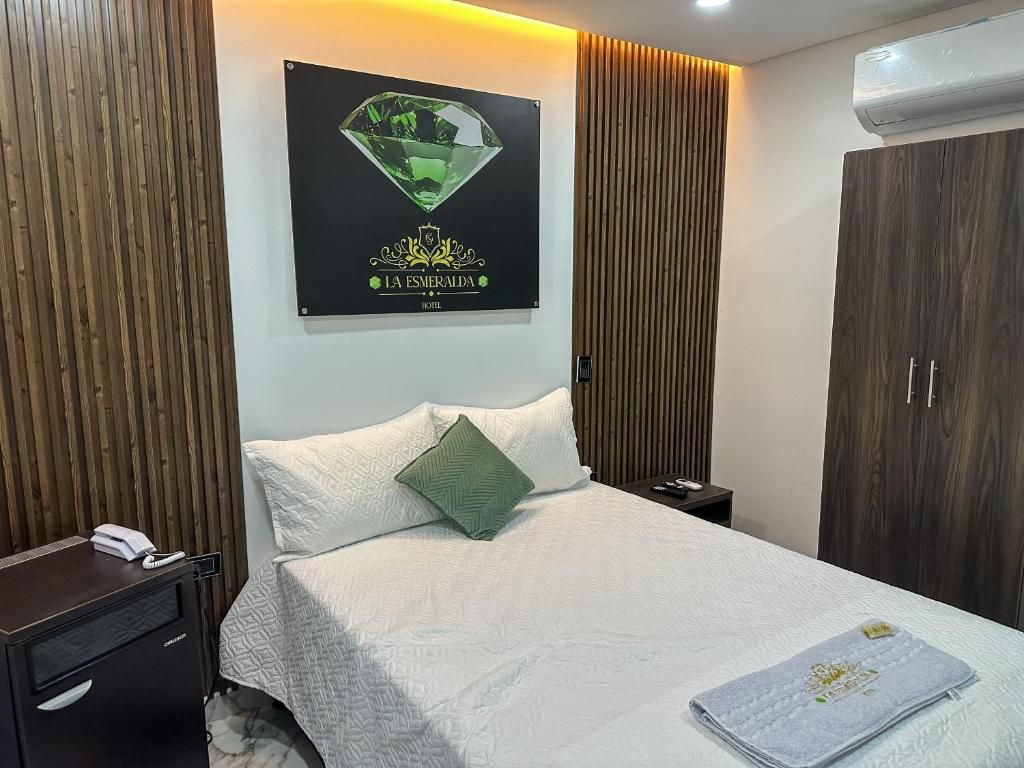 Quarto de hotel com cama, mesa de cabeceira, guarda-roupa de madeira e ar condicionado fixado na parede.