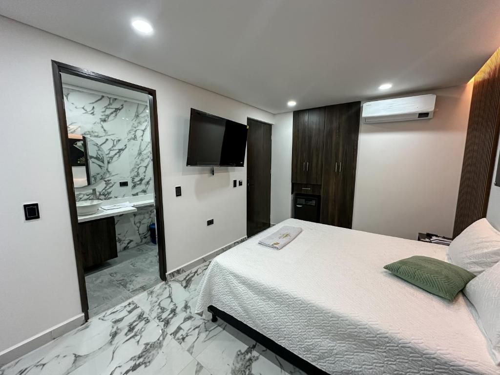 A bedroom with a bed, a television, a wardrobe, and a bathroom with a marble floor.