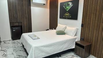 A hotel room with a bed, a nightstand, a wardrobe, and a wall-mounted air conditioner.