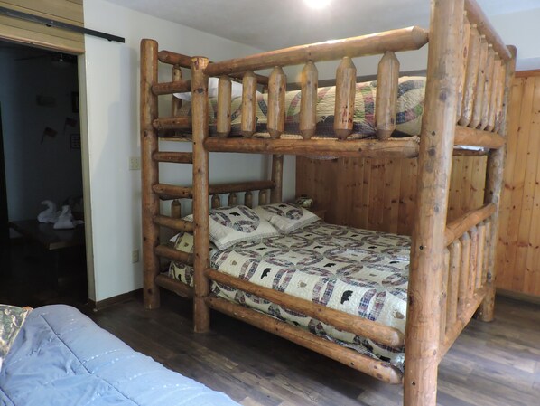 A bunk bed with a ladder, wooden walls, and patterned bedding. - Tranquil 3-bedroom cabin with lots of wildlife. (Pigeon Forge)