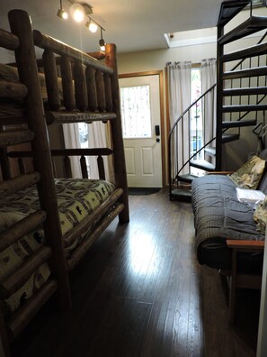 Ein Zimmer mit einem Etagenbett, einer Schlafcouch, einer Treppe und einer Tür mit Fenster.