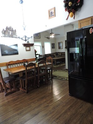 A dining area with a wooden table and chairs, a black refrigerator, and a ceiling fan. - Tranquil 3-bedroom cabin with lots of wildlife. (Pigeon Forge)
