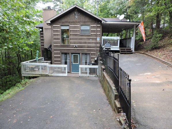 Eine zweistöckige Holzhütte mit Veranda, Satellitenschüssel und Briefkasten.