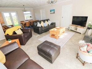 A living room with a sofa, ottoman, coffee table, and a television. - Castle Grove (Milford Haven)