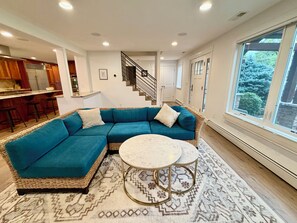 A modern living room with a sectional sofa, a round coffee table, and a view of the outdoors through a large window. - Bright & Spacious Sundance Home with Dedicated Office & Gym (Boulder)