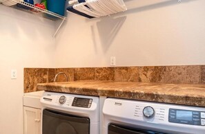 A laundry area with a washing machine and dryer, a countertop, and a shelf above. - Bright & Spacious Sundance Home with Dedicated Office & Gym (Boulder)