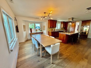 Una cocina amplia con suelo de madera, una isla central y electrodomésticos modernos.