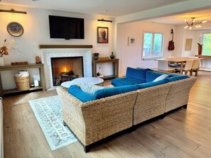 A living room with a fireplace, a television, a dining area, and a guitar. - Bright & Spacious Sundance Home with Dedicated Office & Gym (Boulder)