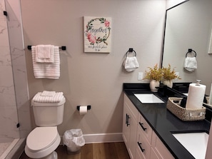 Een badkamer met toilet, wastafel, spiegel, handdoekhouder en een decoratief bord.