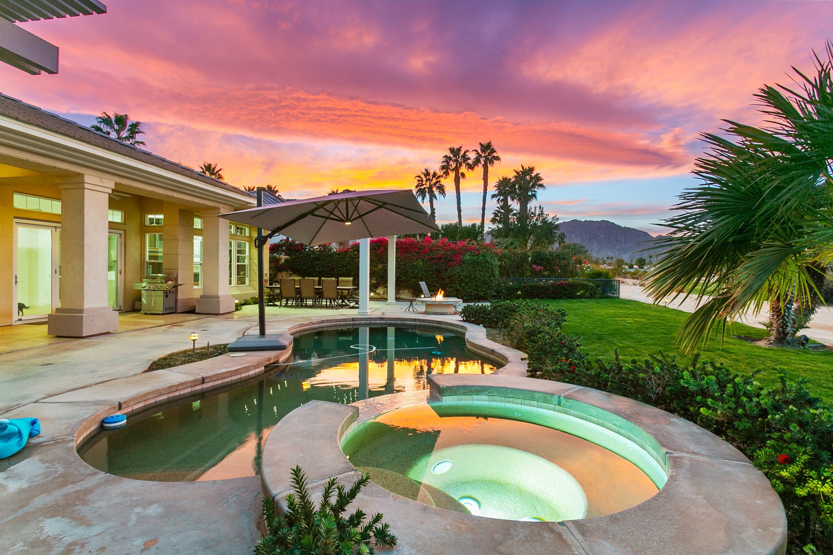 A residential property with a swimming pool, outdoor seating, and a view of mountains.