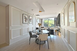 A dining area with a round table, chairs, and a vase of flowers. - Luxury Hillside 2 Bed apt w/Mountain & Ocean Views in vibrant Cape Town (Cape Town)