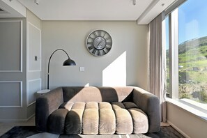 Ein modernes Wohnzimmer mit einem großen Fenster, einer runden Wanduhr und einer Stehlampe.