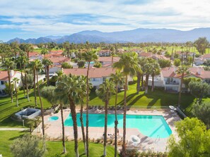 A residential area with a swimming pool surrounded by palm trees and houses with red-tiled roofs. - 2 Bedroom Desert Falls Condo (Palm Desert)