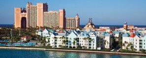 A coastal hotel with multiple buildings, a swimming pool, and a clear view of the ocean. - 1 Bedroom Premium – Harborside Resort at Atlantis – Full Resort Access (Paradise Island)