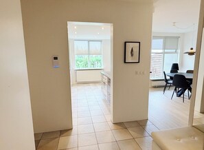 A modern interior with a kitchen area, dining space, and a view through a doorway. - Bright apartment at the heart of Kópavogur (Kópavogur)