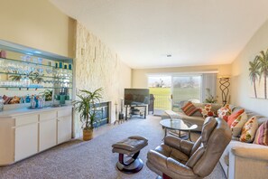 A living room with a sofa, a coffee table, a TV, and a balcony with a view. - 2 Bedroom Condo in Desert Falls (Palm Desert)