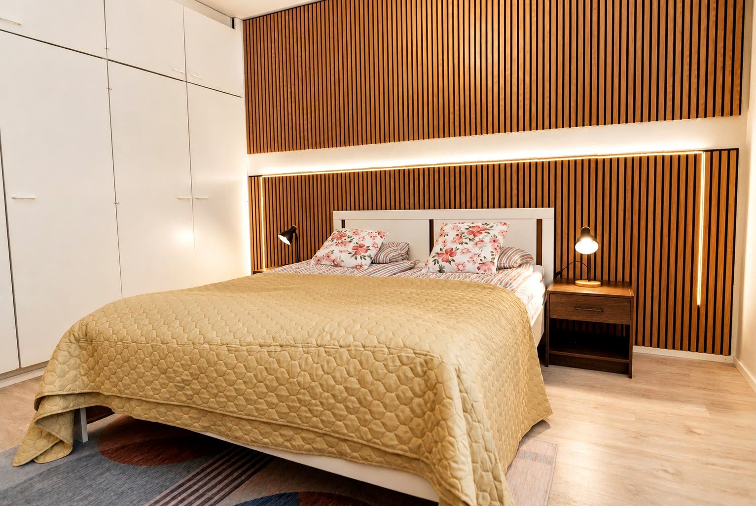 A bedroom with a bed, nightstands, a wooden slatted headboard, and a wardrobe.