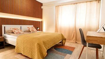 A modern bedroom with a bed, bedside table, and a desk with a chair.