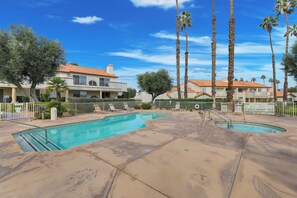 A swimming pool with a concrete deck, surrounded by palm trees and a fenced area. - Desert Falls 2 Bedroom Condo (Palm Desert)