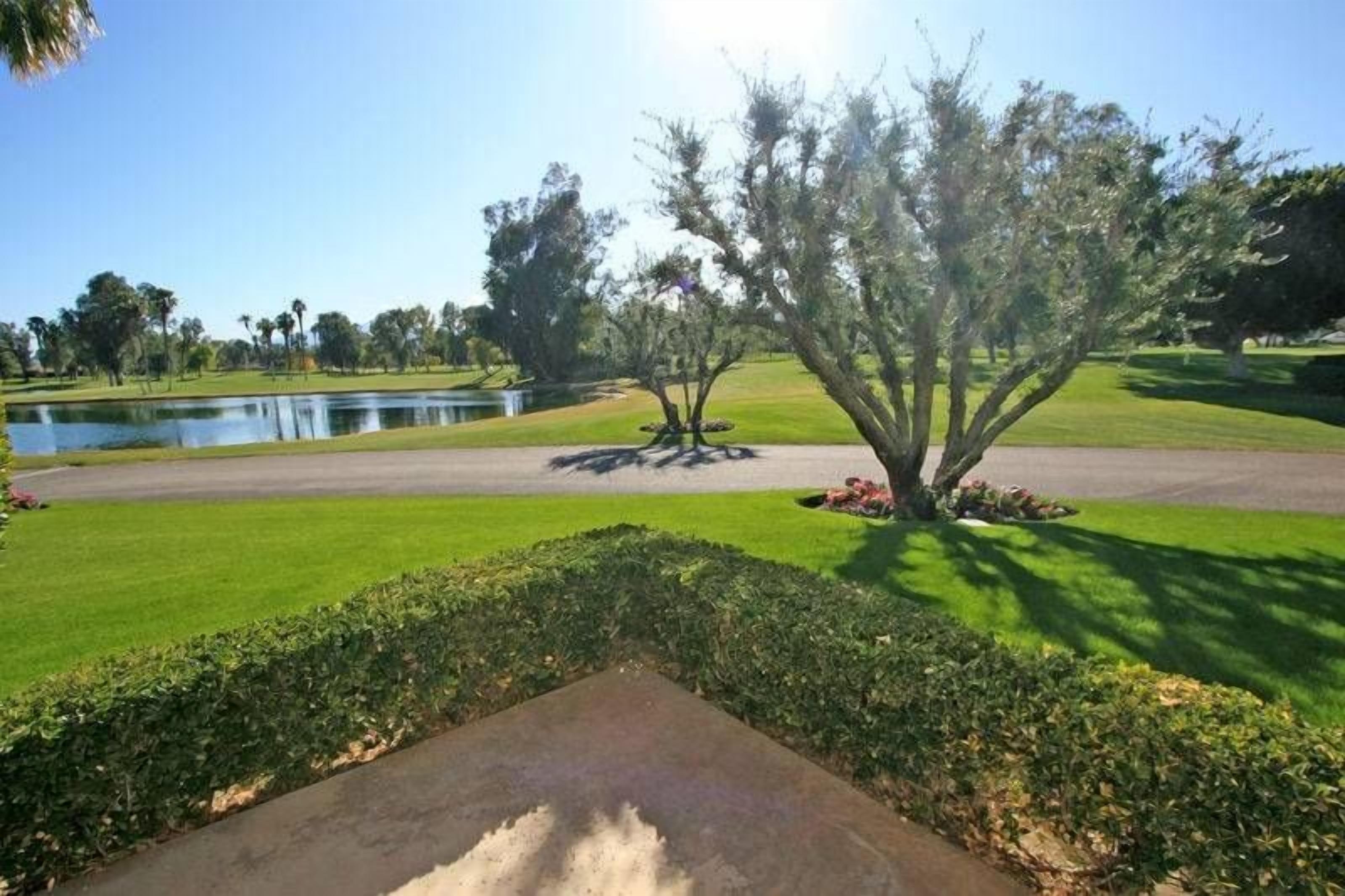 A golf course with a pond, manicured grass, and trees.