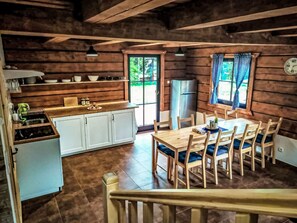 A rustic cabin interior with a kitchen, dining area, and a large window.