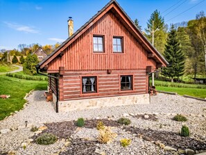 A wooden cabin with a stone foundation, two windows, and a chimney.