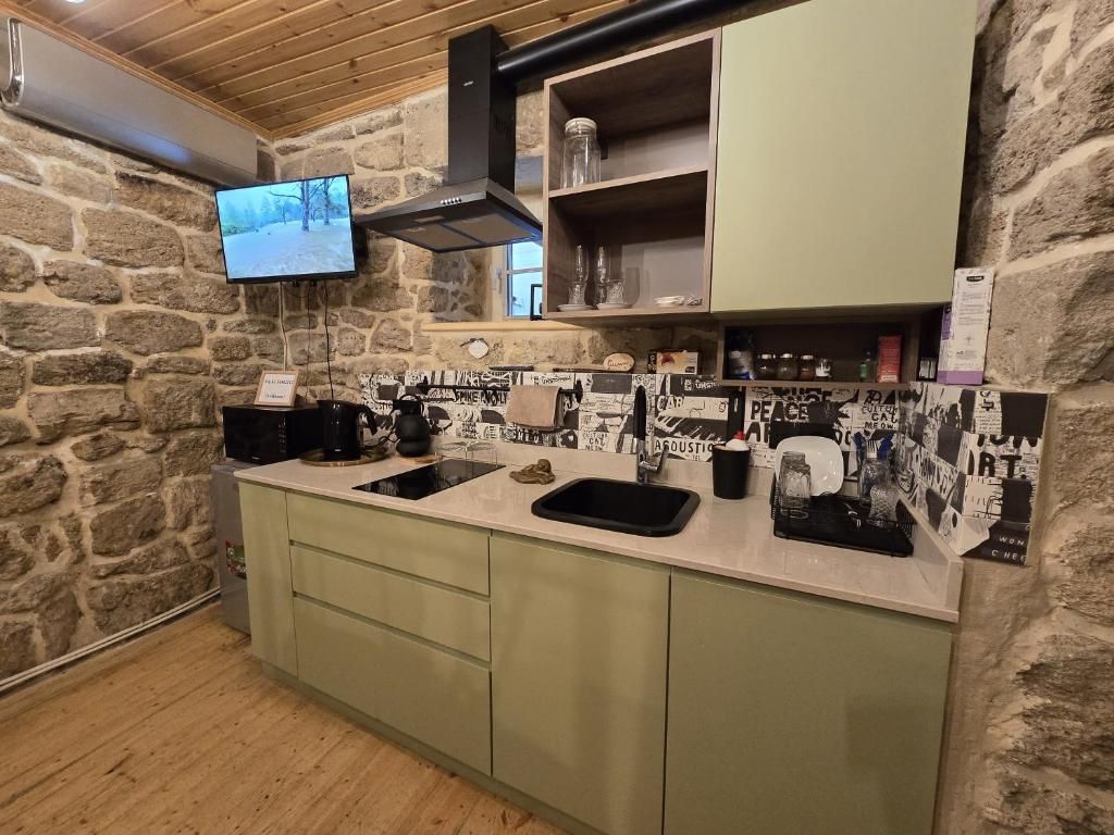 A kitchen with a stone wall, a flat-screen TV, and a variety of kitchenware.
