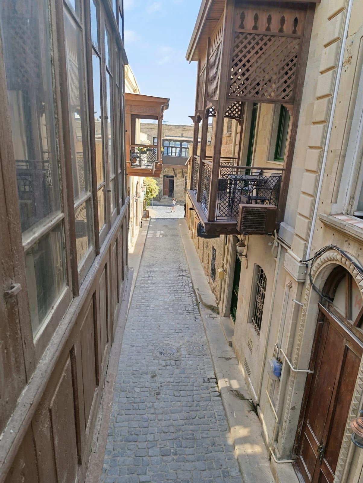 Eine enge Kopfsteinpflasterstraße, gesäumt von Gebäuden mit Balkonen und großen Fenstern.