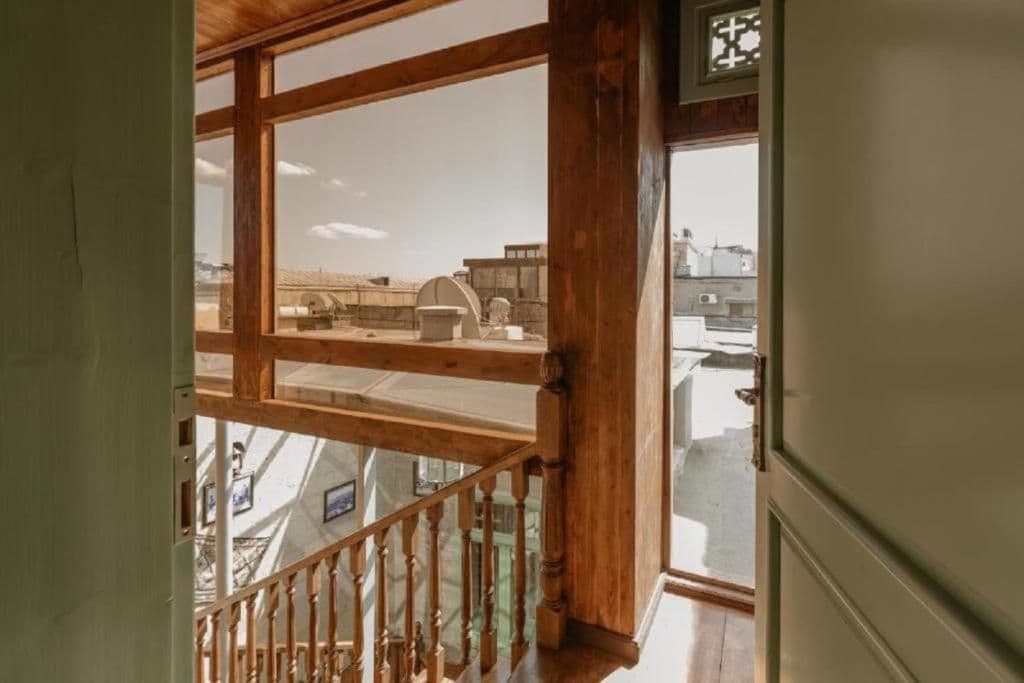 A wooden staircase leading to a balcony with a view of industrial buildings.
