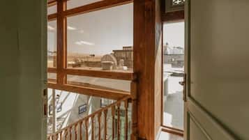 A wooden staircase leading to a balcony with a view of industrial buildings.