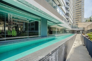 A modern building with a swimming pool, glass walls, and a covered walkway. - Well-located Apt. in Condo. w/ Pool Fre0504 (São Paulo)