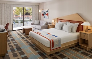 Een hotelkamer met een groot bed, een bank, een bureau en uitzicht op het omliggende landschap.
