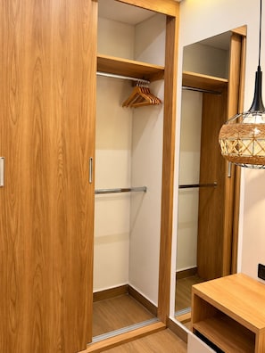 Ein hölzerner Kleiderschrank mit Spiegel, Kleiderstange und einer kleinen Holzablage.