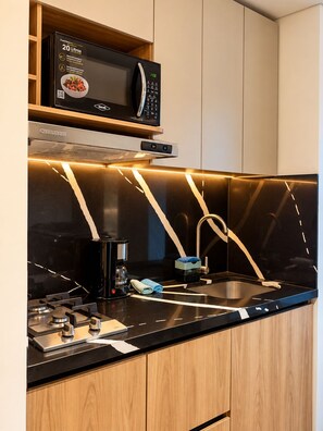 A modern kitchen with a built-in microwave, a coffee maker, and a sink. - 201- A/C • Balcony • 2 Workspaces • Washing Machine • Unicentro (Medellín)
