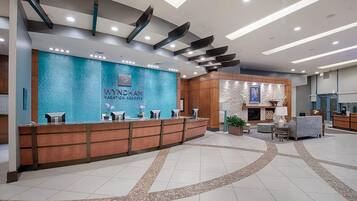 A reception area with a blue textured wall, a wooden reception desk, and a seating area with a fireplace.