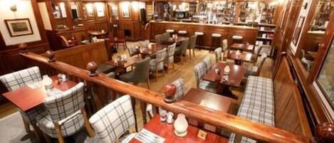 Un restaurante con varias zonas de estar, incluidas cabinas y mesas, y un bar al fondo.