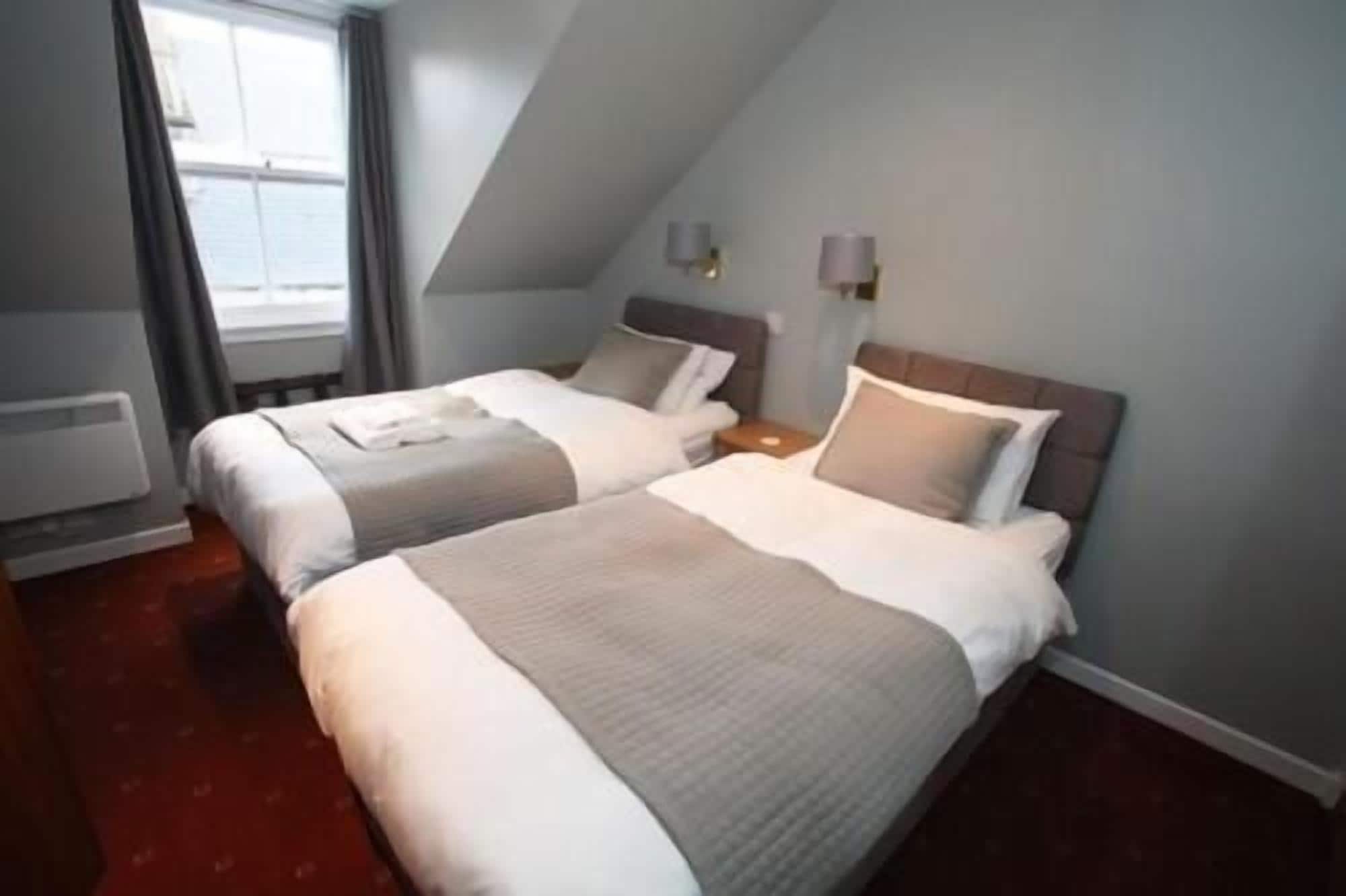 Habitación de hotel con dos camas, una ventana y un radiador.