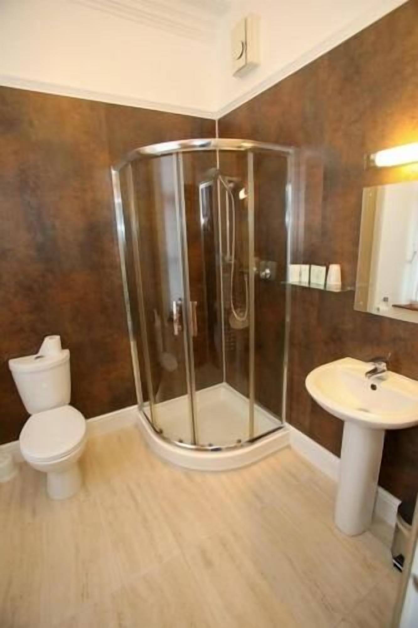 A bathroom with a glass-enclosed shower, a white sink, and a toilet.