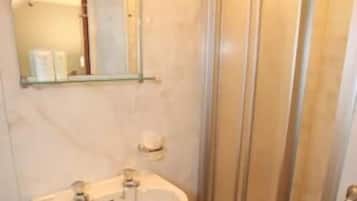 A bathroom with a sink, mirror, and glass shower enclosure.