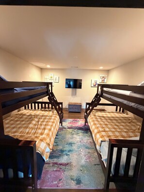 A room with bunk beds, a flat-screen TV, and a colorful rug. - Perfect 6-bedroom barn with Pool in lovely McKinney (McKinney)